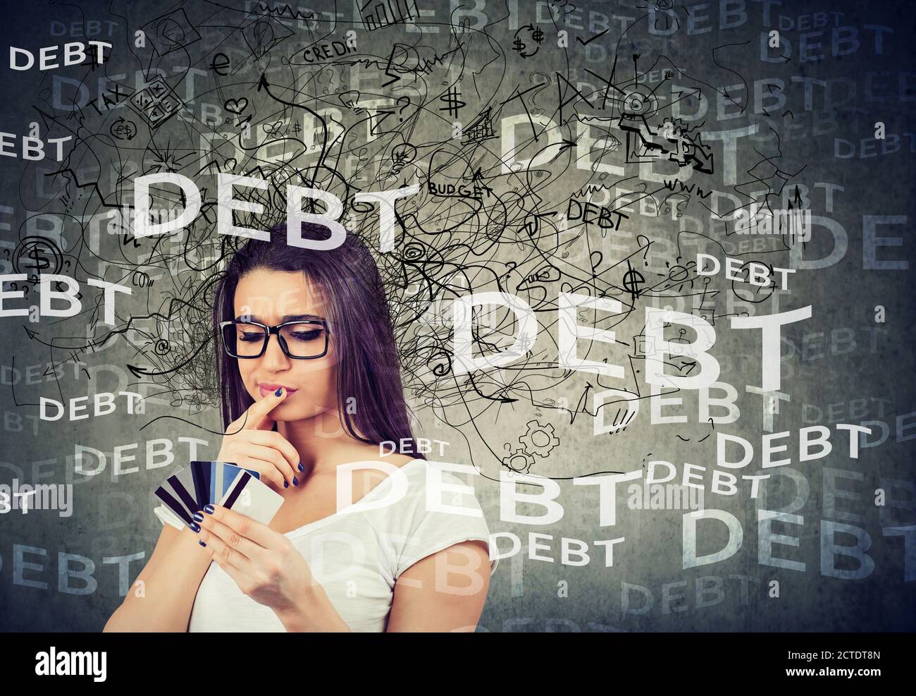 Gestresste junge Frau, die viele Kreditkarten mit riesigen Schuldenstand betrachtet. Stockfoto