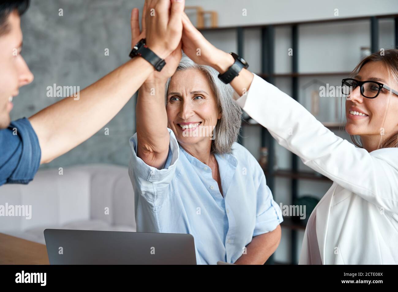 Glückliche alte Mentorin Lehrer geben hohe fünf junge Mitarbeiter Studenten Team. Stockfoto