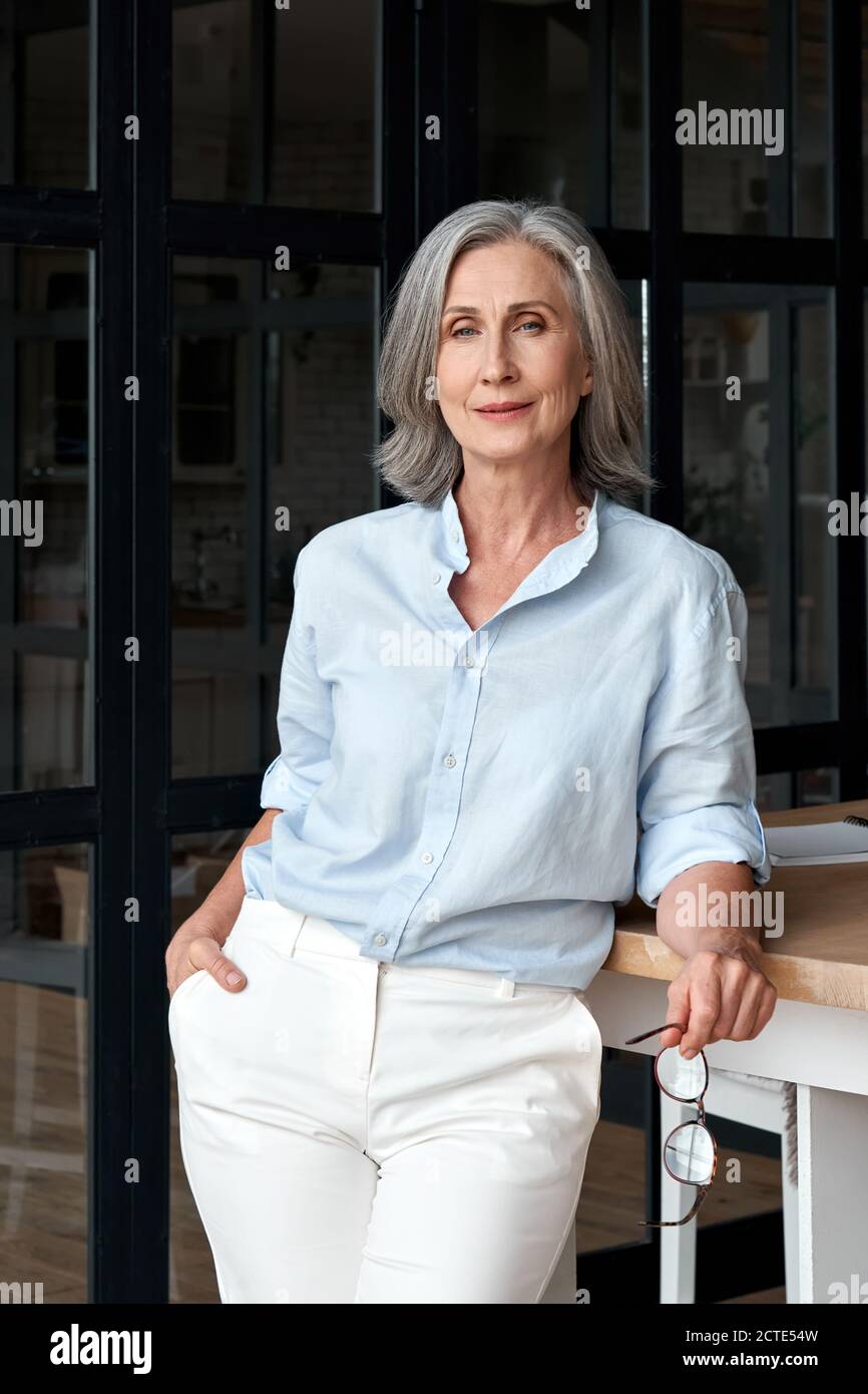 Selbstbewusste reife Frau mittleren Alters stehend am Büroarbeitsplatz, Porträt. Stockfoto