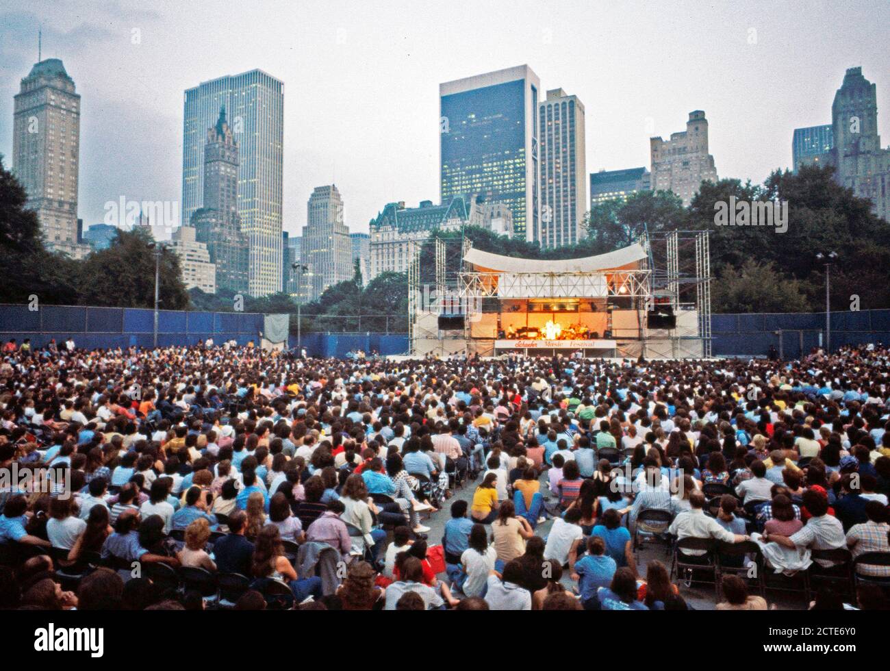 Versammelt auf der Schaefer Musikpavillon im Central Park zu hören Sängerin Judy Collins auch einen dramatischen Blick auf die Türme von Midtown Manhattan Stockfoto