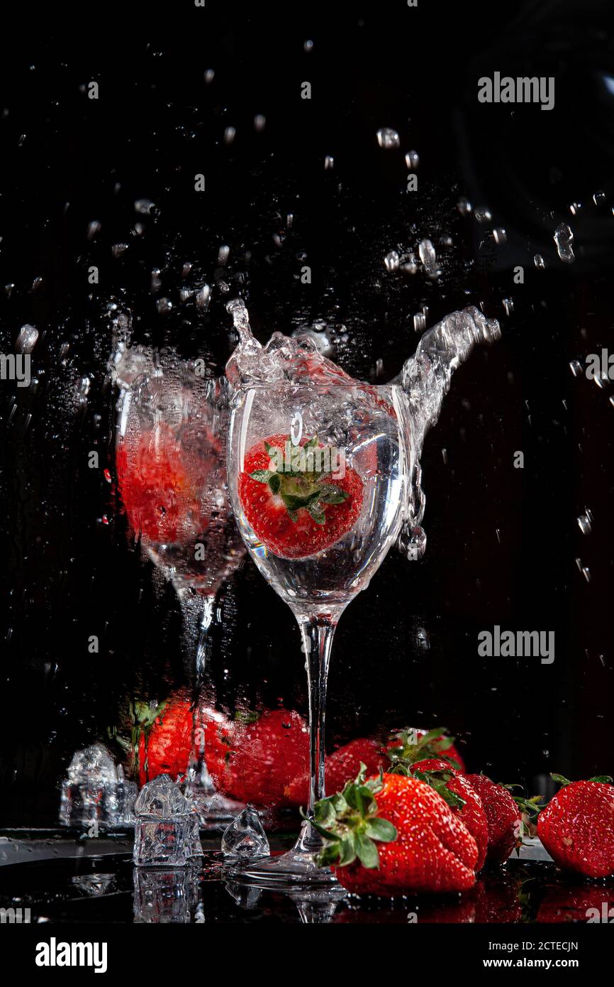 Erdbeere fallen in das Glas mit Wasser Stockfoto