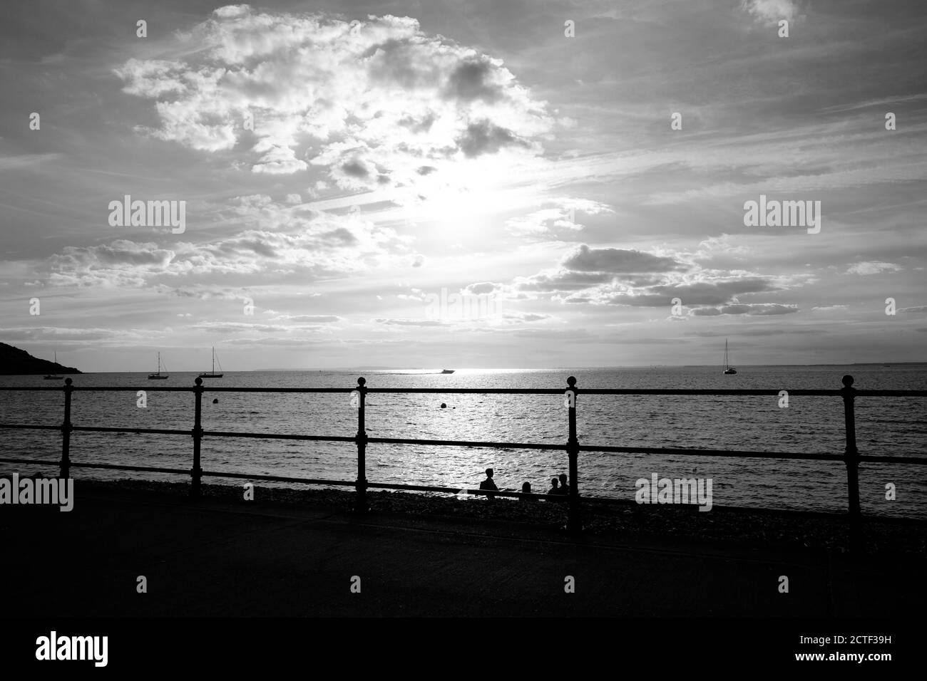 Eine Familie am Strand von Totland Bay Isle of Wight Abend Sonne Sonnenuntergang hinter in Silhouette Yachten an Anker in der Bucht Stockfoto