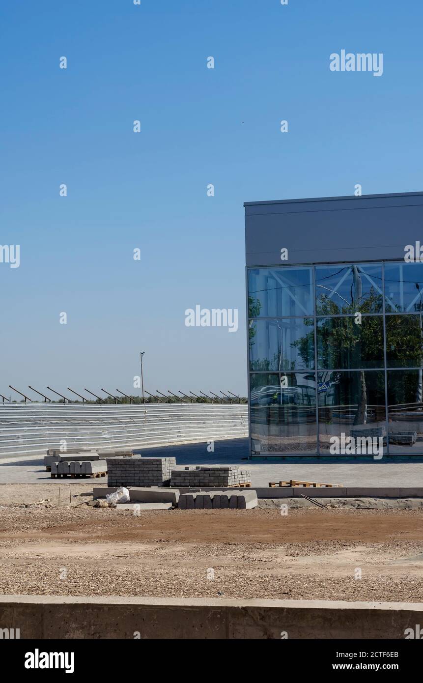 Die Fassade eines im Bau befindlichen Firmengebäudes aus Glas und Beton. Unvollendeter Bau von Gewerbeimmobilien. Rasen ohne Gras Stockfoto