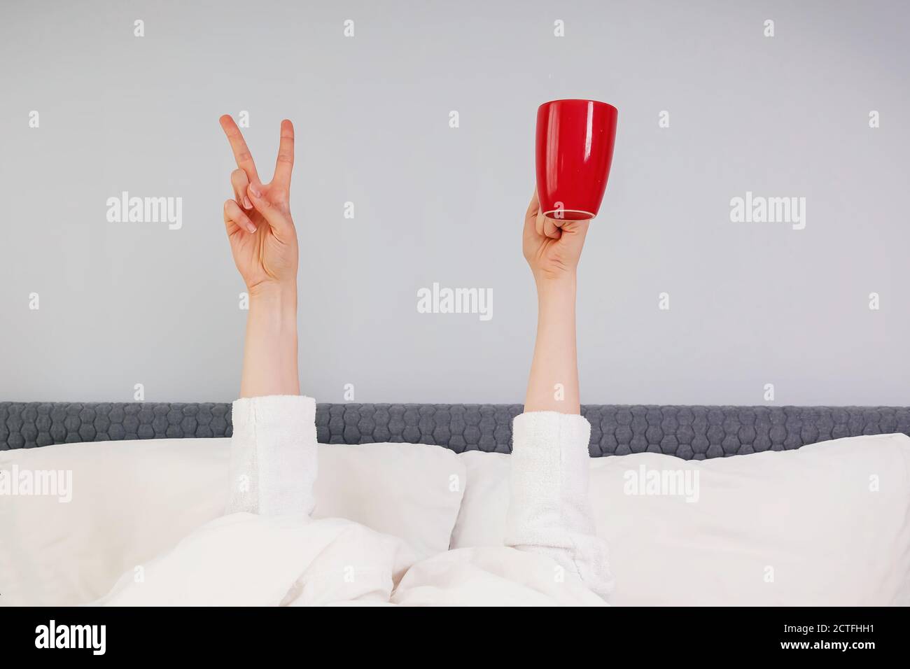 Hände halten rote Tasse und V-Zeichen stehen unter Die Decke Stockfoto
