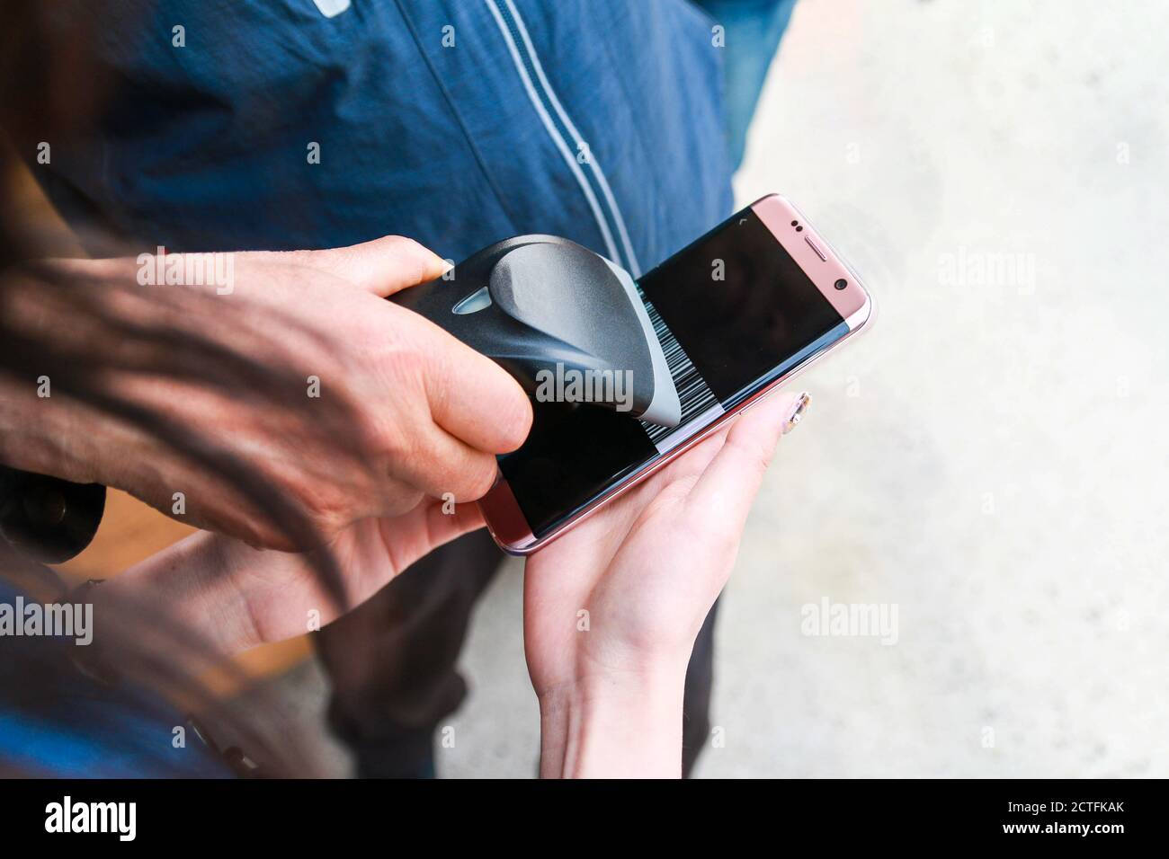 Hand mit einem elektronischen Strichcode-Scanner, um einen Barcode von einem Handtelefon zu scannen. Stockfoto