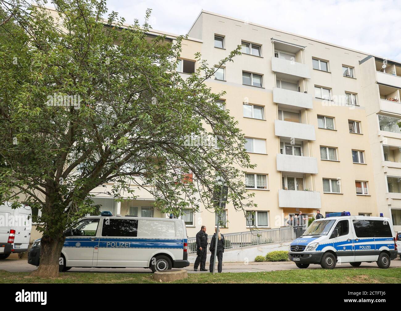 23. September 2020, Sachsen-Anhalt, Weißenfels: Fahrzeuge und Bundespolizisten stehen bei einer Durchsuchung vor einem Wohngebäude. Seit den frühen Morgenstunden führt die Bundespolizei Durchsuchungen in fünf Bundesstaaten im Zusammenhang mit dem illegalen Schmuggel von Arbeitern für die Fleischindustrie durch. Bei dem bundesweiten Überfall auf den illegalen Schmuggel von Arbeitnehmern für die Fleischindustrie steht Weißenfels im Fokus. Foto: Jan Woitas/dpa-Zentralbild/dpa - ACHTUNG: Nummernschilder wurden aus persönlichen Gründen verpixelt. Stockfoto