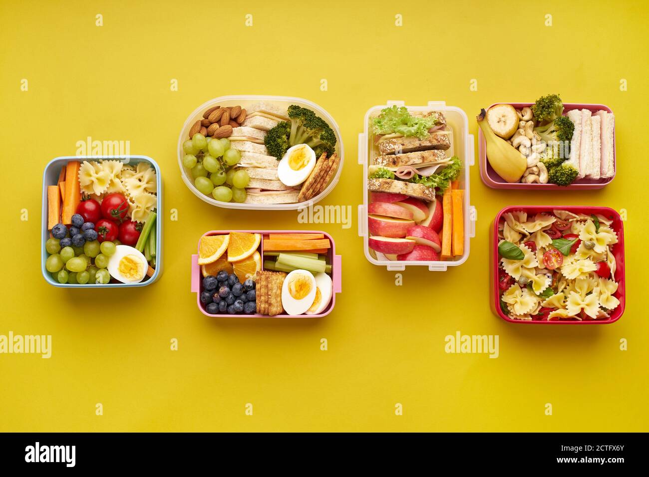 Draufsicht auf Schullunchboxen mit verschiedenen gesunden und nahrhaften Mahlzeiten Auf gelbem Hintergrund mit Kopierbereich Stockfoto