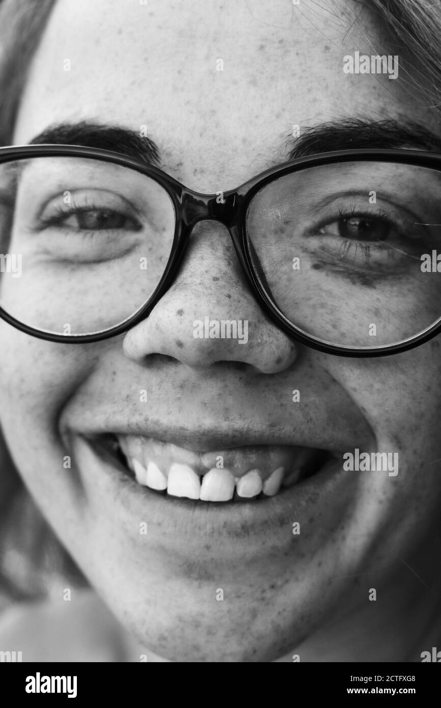 Nahaufnahme Porträt eines Lächeln Frau Mädchen mit Sommersprossen. Porträt eines Mädchens im Freien im Sonnenlicht. Gesicht mit Brille, Nahaufnahme. Glückliches Gesicht Stockfoto