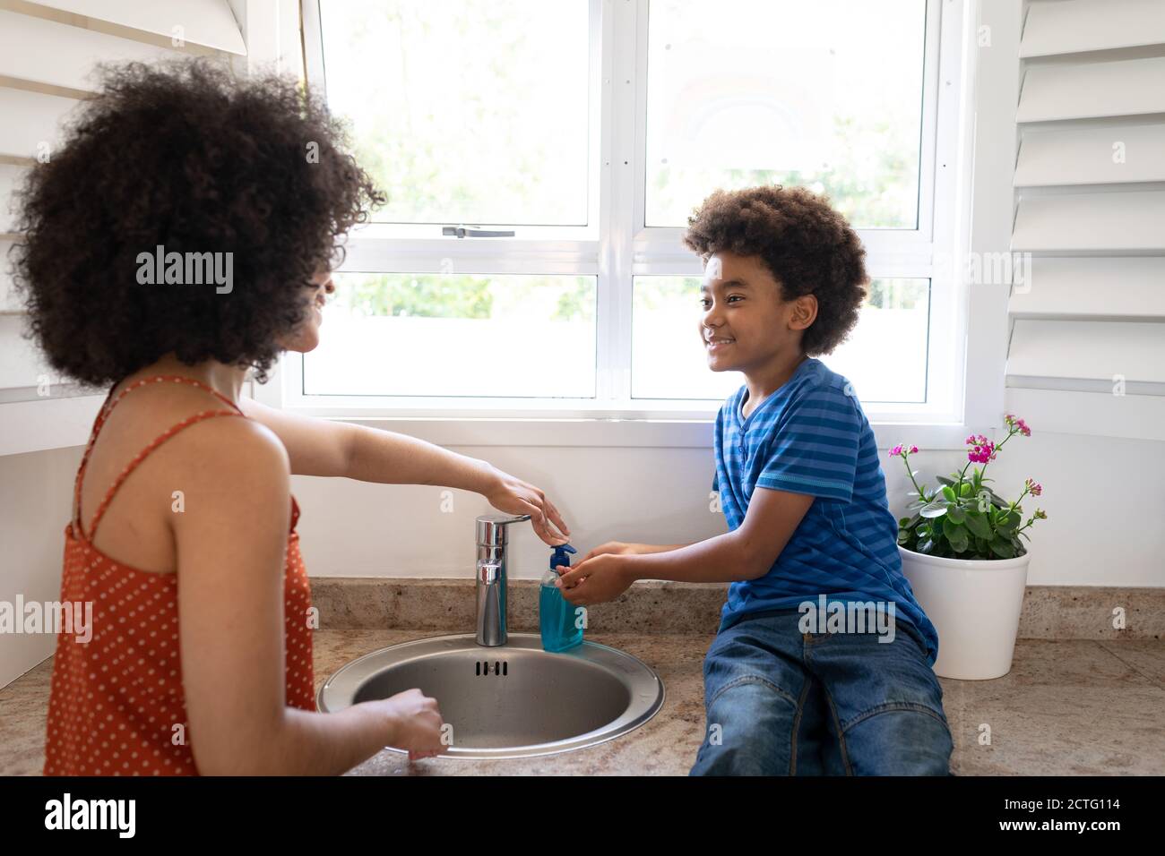Mutter hilft Sohn, seine Hände zu Hause zu waschen Stockfoto