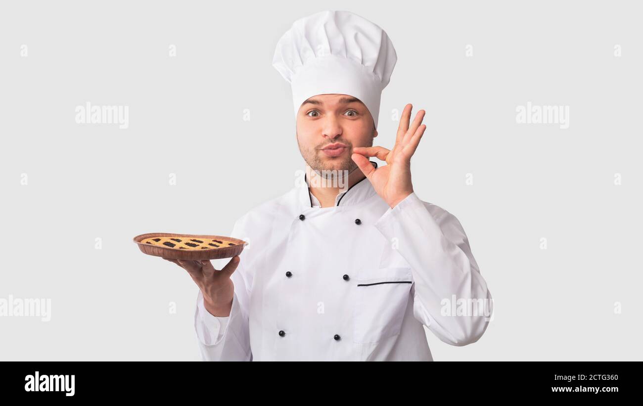 Chef Man Holding Pie Gesturing Zip Ihre Lip, Weißer Hintergrund Stockfoto