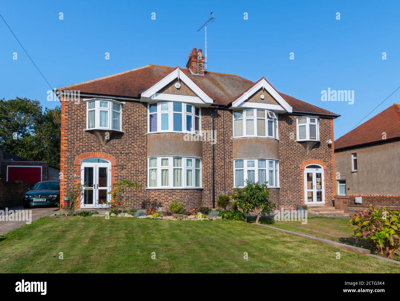 Große zweistöckige britische Doppelhaushälfte aus den 1930er Jahren aus Ziegelstein mit gebogenen Erkerfenstern in West Sussex, England, Großbritannien. Stockfoto