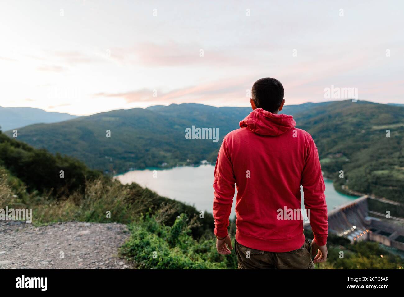 Junger Mann, der den Blick auf den See bei Sonnenuntergang genießt Stockfoto