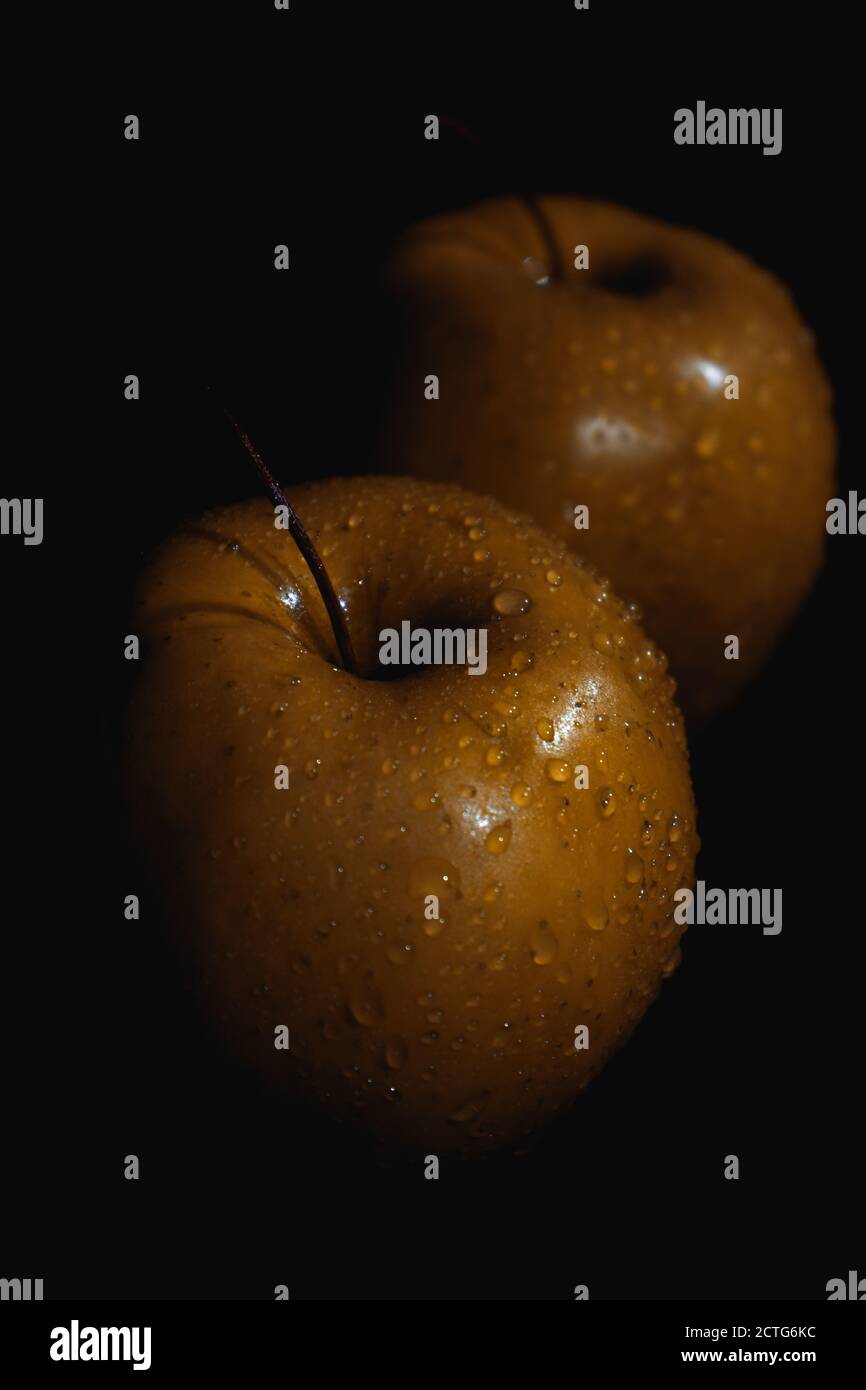 Apfelfrucht, abstrakter Schatten, schwarzer Hintergrund, goldener Apfel, Wassertropfen Stockfoto