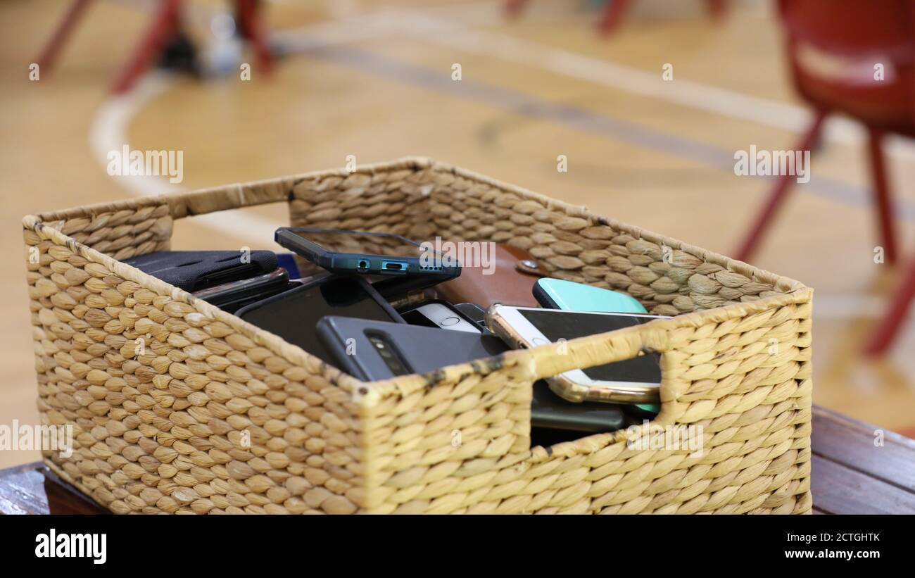 Handy kostenlos Klassenzimmer und Schulen. Ein Speichercontainer, der mit mehreren Telefonen von Studenten oder Benutzern gefüllt ist. Rohrkorb mit Mobile gefüllt Stockfoto
