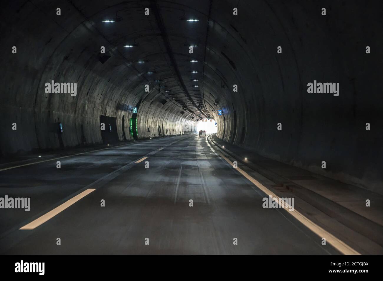 Fahrt durch einen dunklen Tunnel auf einer Autobahn mit einem Blick auf das Licht am Ende des Tunnels Stockfoto