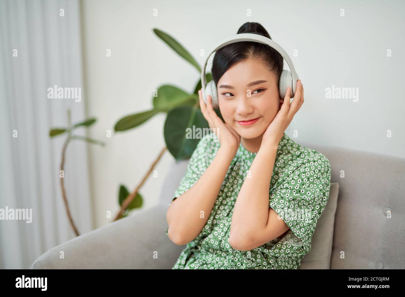 Asiatische Frau, die zu Hause mit Kopfhörern Musik hört Wireless-Technologie mit Kopierbereich. Stockfoto