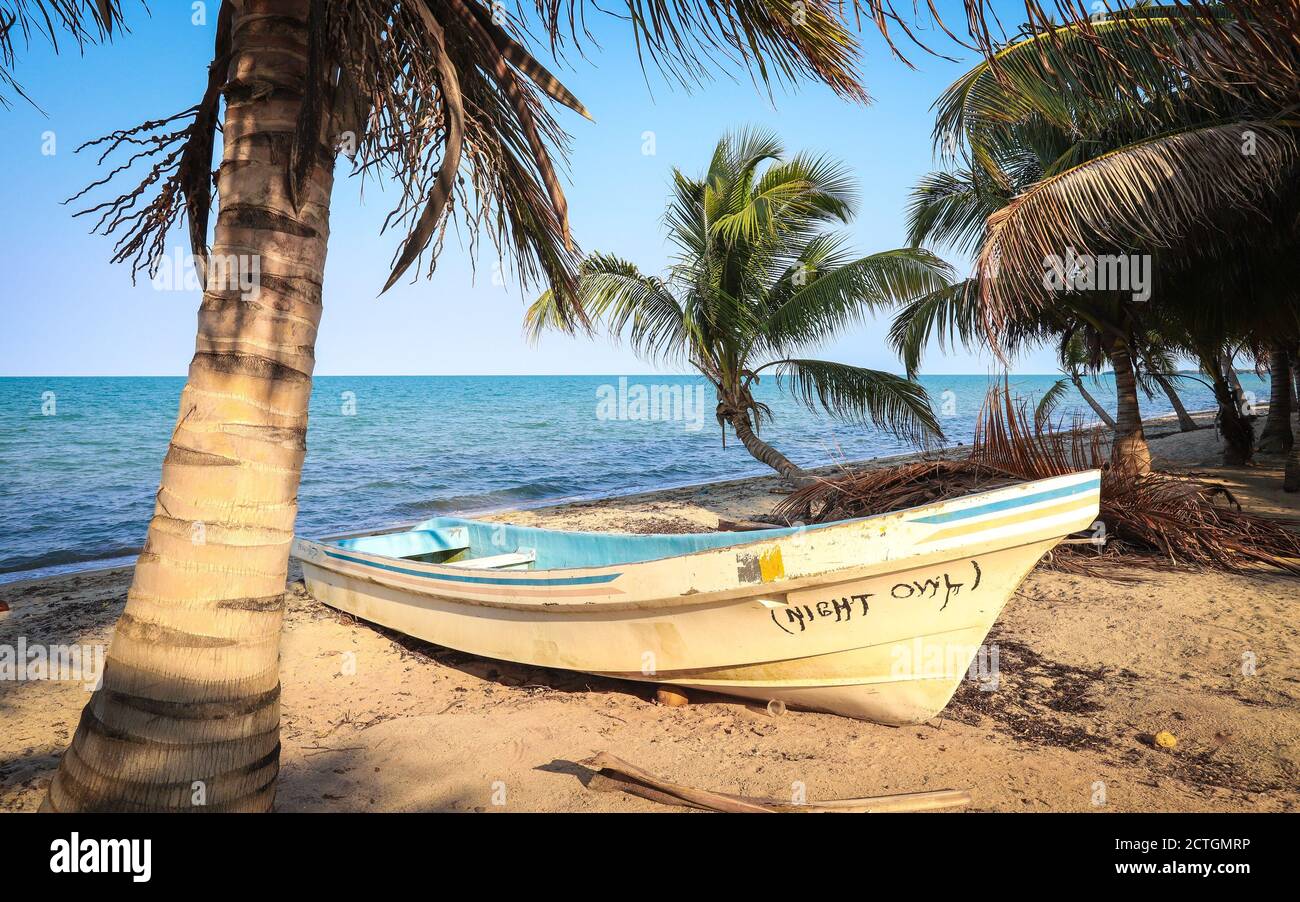 HOPKINS BEACH, BELIZE - Apr 18, 2019: Ein Boot sitzt am Strand in der Belize Stadt Hopkins Beach in einer idyllischen Szene. Stockfoto