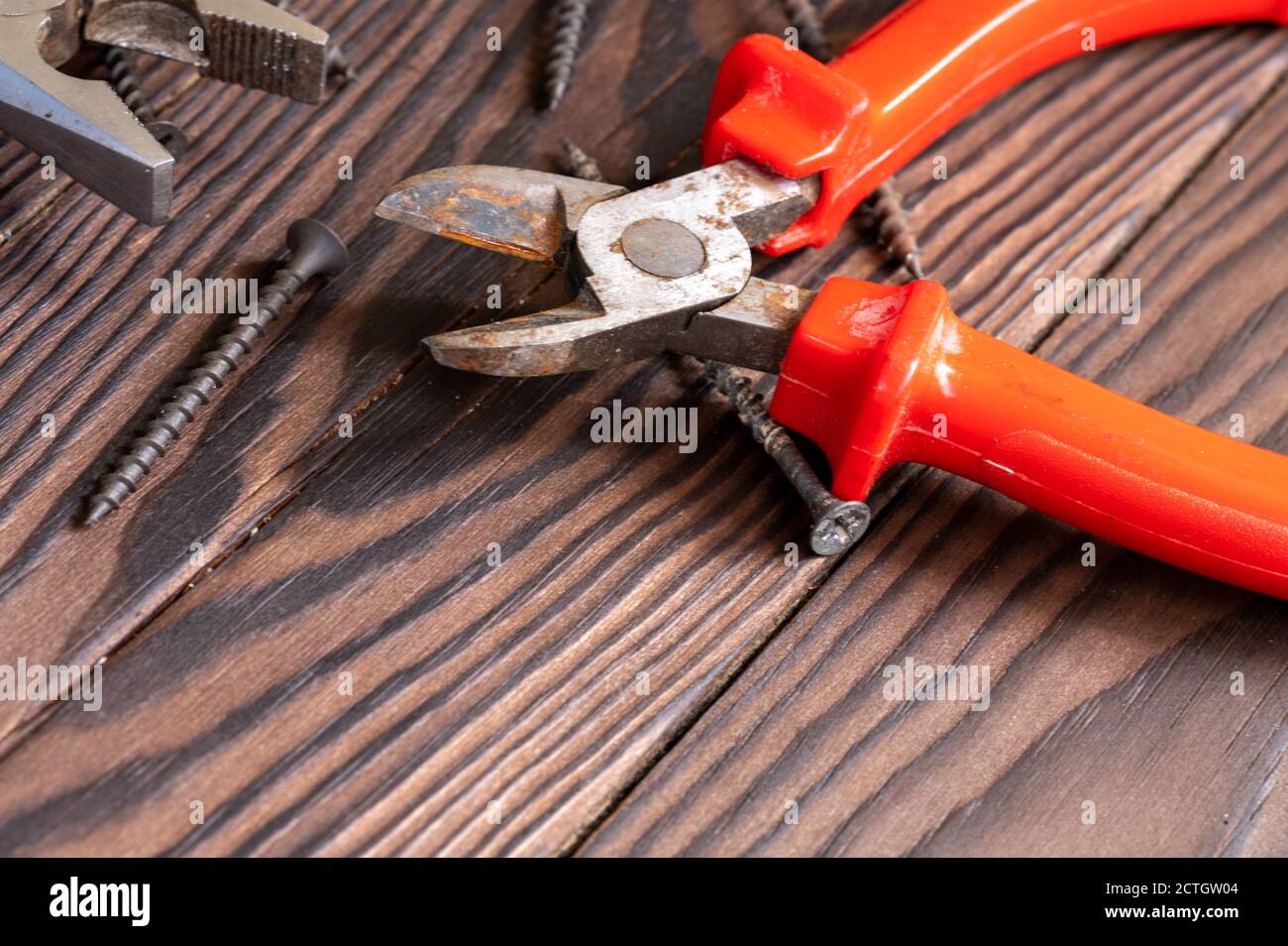 Zangen, Seitenschneider, selbstschneidende Schrauben auf Holzhintergrund, Nahaufnahme, selektiver Fokus Stockfoto