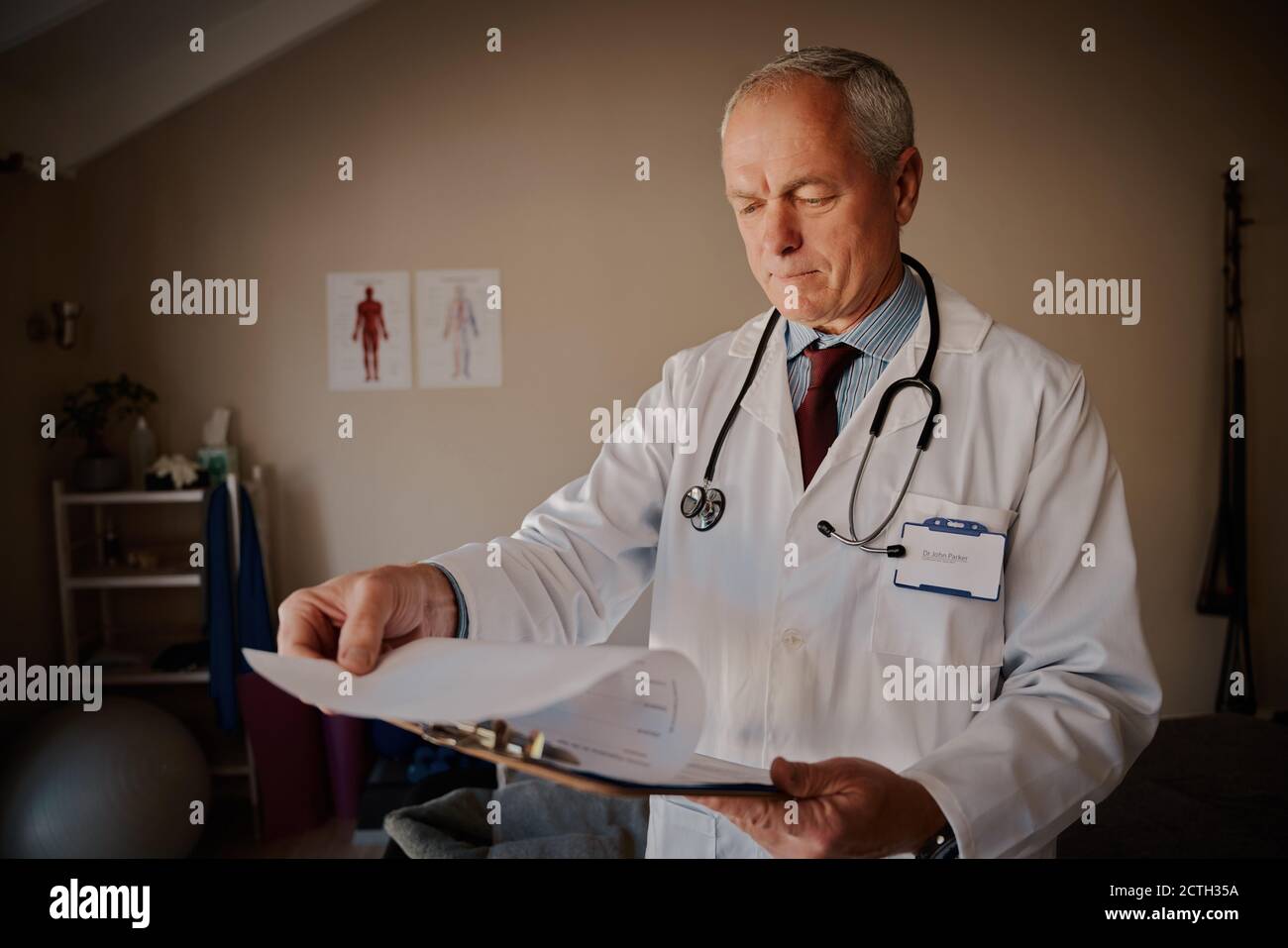 Senior männlich Arzt hält Zwischenablage Überprüfung Berichte in modernen Hause Krankenhaus Stockfoto