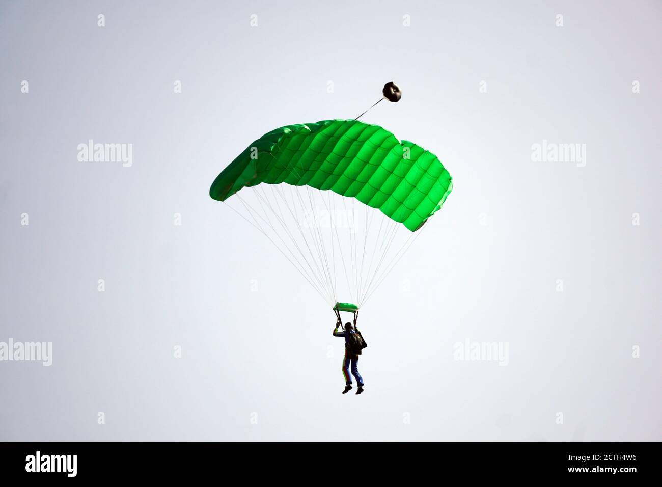 Der einzelne Fallschirmspringer, der aus dem Flugzeug gesprungen ist, benutzt einen Fallschirm, um zu landen. Einfaches Konzept mit Copy Space Photograph. Stockfoto