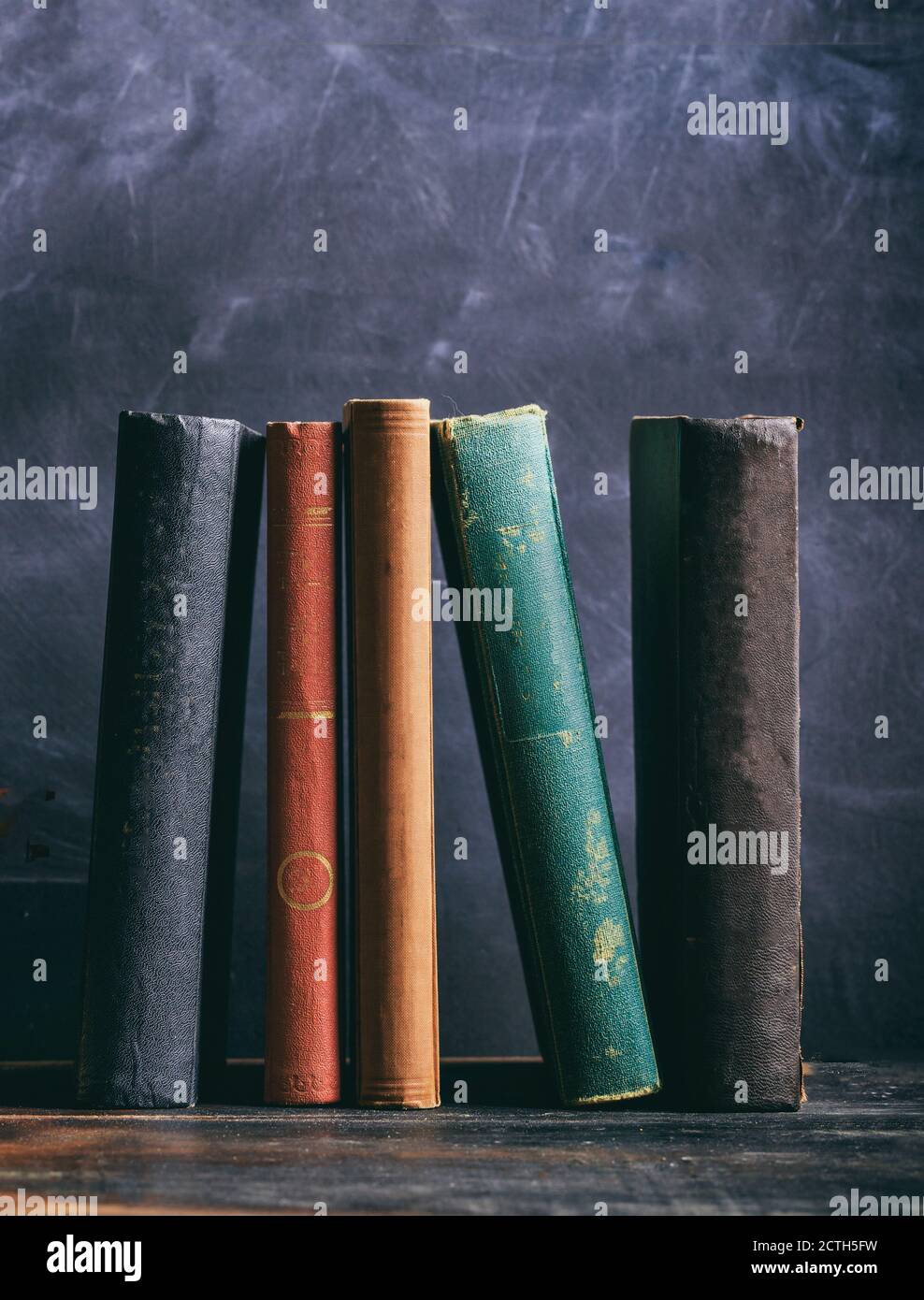 Alte Bücher auf einem Holzregal, schwarze Bretterhintergrund. Gesetz, Geschichte Bibliothek Regal, vertikale Aufnahme Stockfoto