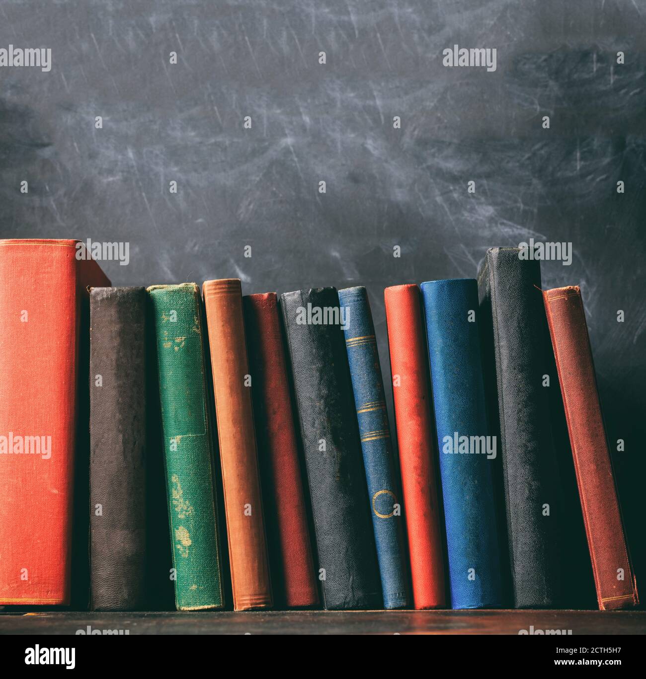 Alte Bücher auf einem Holzregal, schwarze Bretterhintergrund. Recht, Geschichte Bibliothek Regal, Kopieraum Stockfoto
