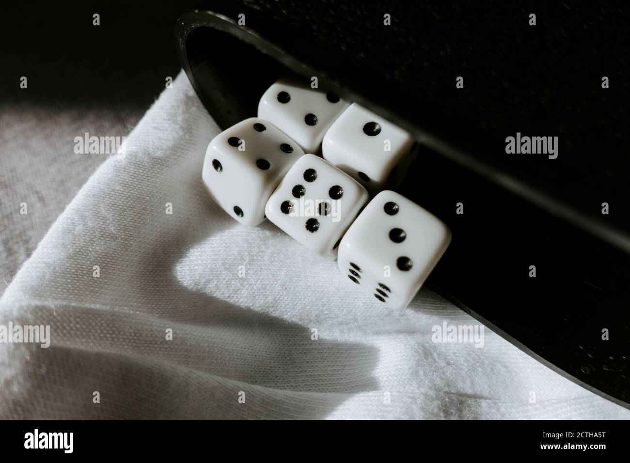 Fünf Würfel mit verschiedenen Zahlen und Tasse im Hintergrund Stockfoto