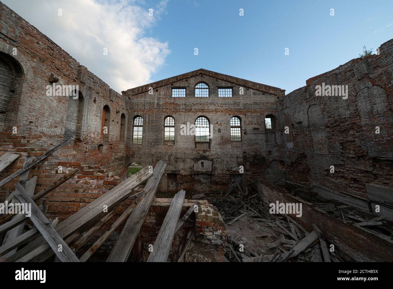 Altes, zerstörtes Ziegelgebäude, Wände. Ohne Dach, unter einem offenen blauen Himmel. Müllhaufen im Inneren Stockfoto