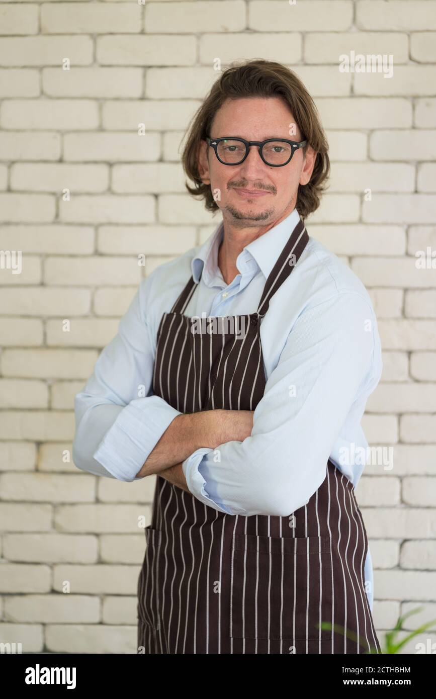 Glücklicher Gärtner Porträt, schöner junger Mann auf Wand Backstein Hintergrund Blick auf die Kamera Stockfoto