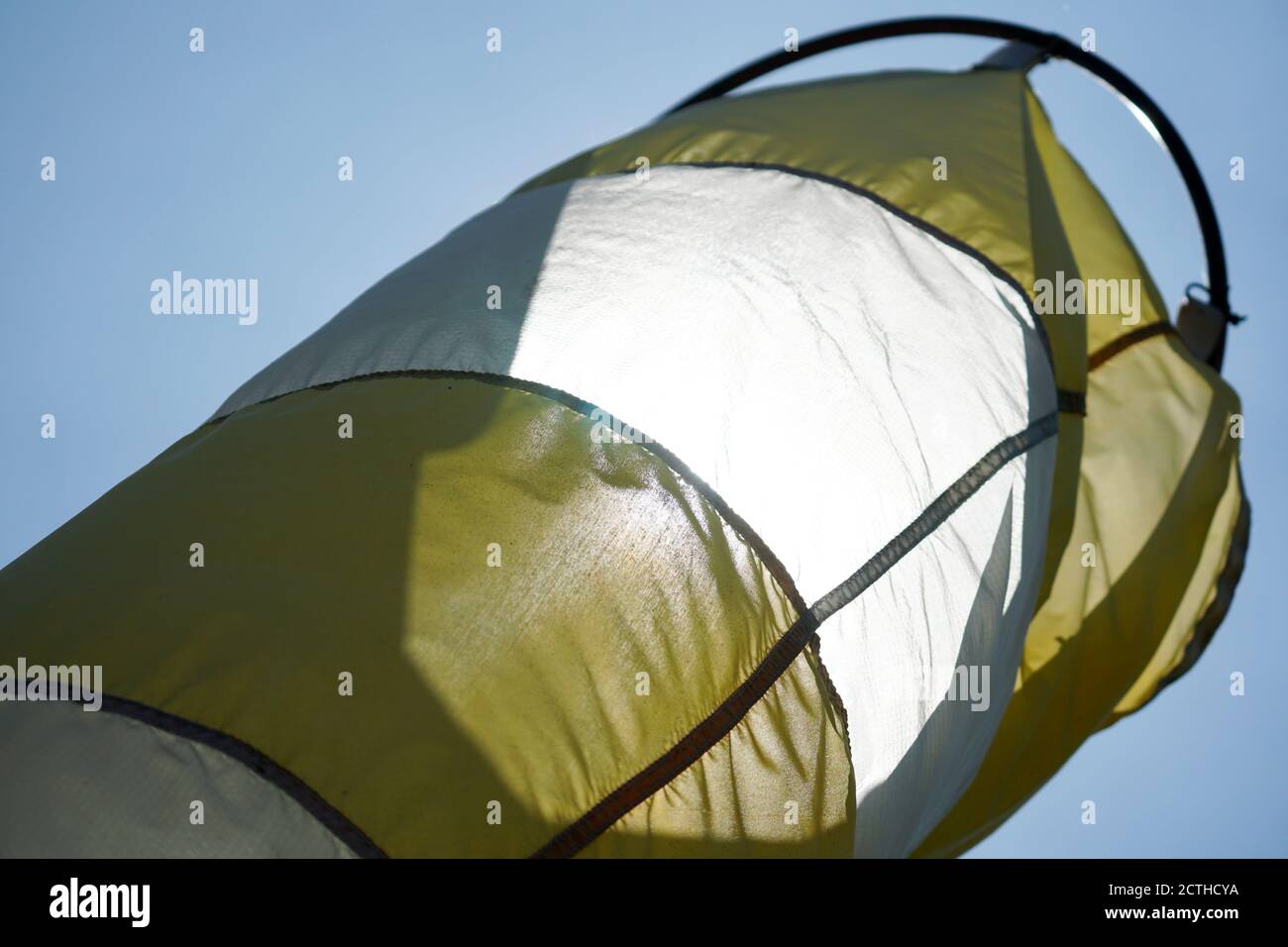 Weiß - gelbe Windsocke auf der Stange auf dem blauen Himmel Hintergrund mit Kopierraum aufgenommen. Stockfoto