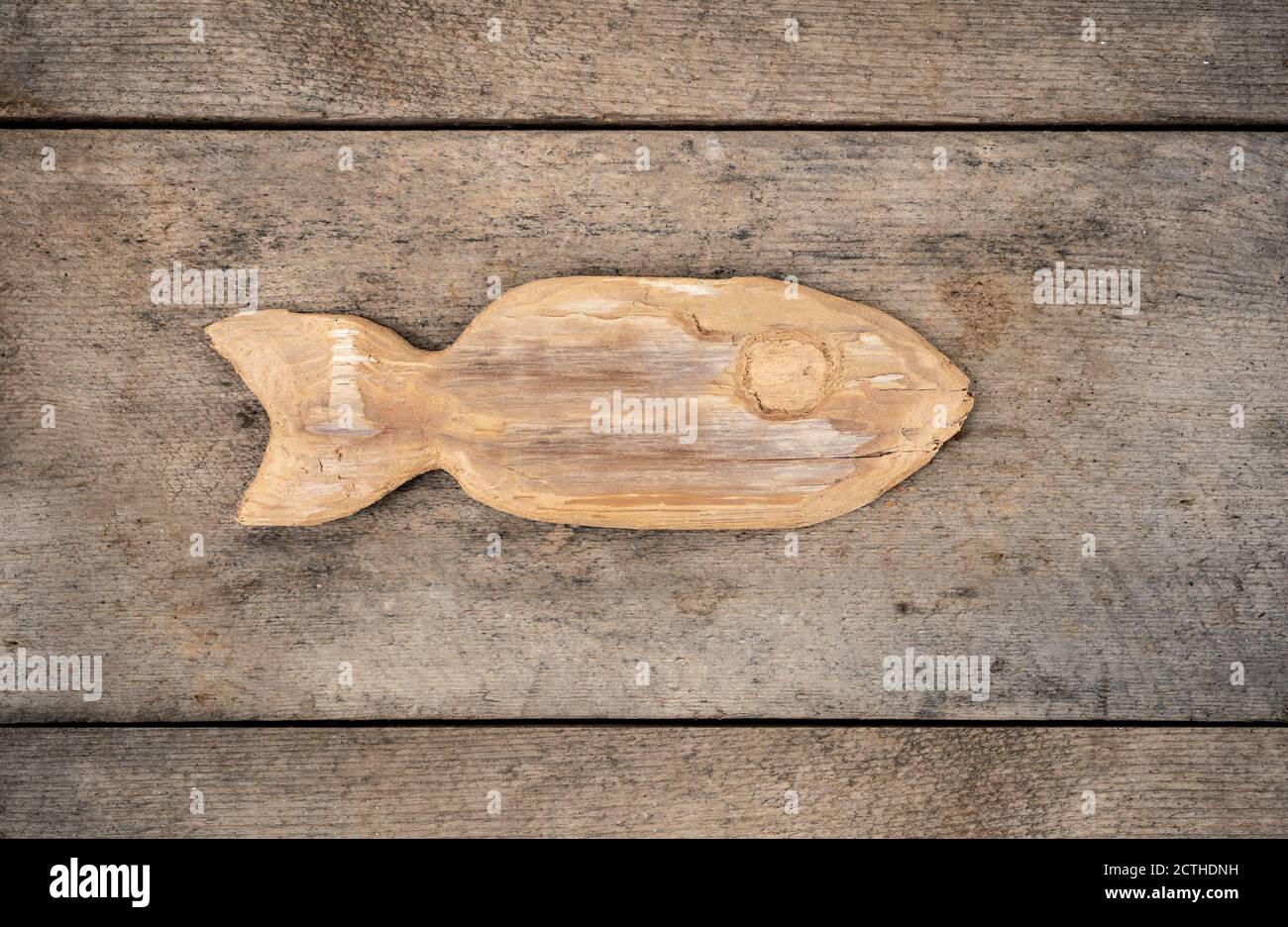 Handgeschnitzter Holzfisch auf Holzhintergrund. Konzept für Fischerei oder Volkskunst. Holz ist alt und verwittert. Volkskunst Stockfoto