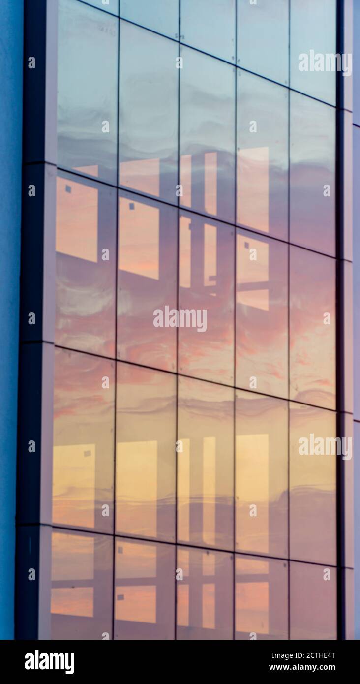 Feuriger Morgenhimmel durch EIN Glasgebäude gesehen Stockfoto