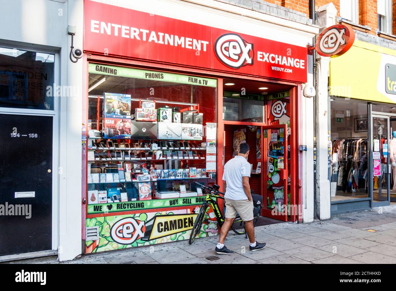 Ein Mann geht an einem ungewöhnlich warmen späten Septembernachmittag, London, vorbei an einer Filiale von CEX Entertainment Exchange in der Camden High Street Stockfoto