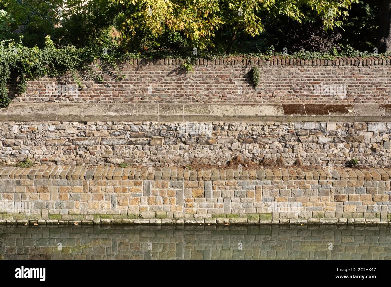 Alte Backsteinmauer Kai im Wasser des Flusses Jeker in Tongeren, Belgien gespiegelt. Die römische Stadtmauer stammt aus dem 4. Jahrhundert n. Chr. Stockfoto