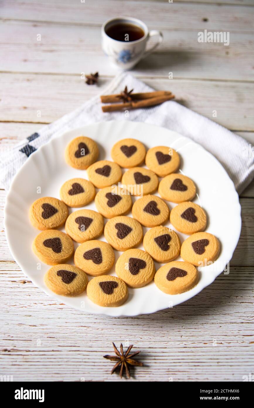 Draufsicht auf Schokolade herzförmige Kekse in einem weißen Teller und schwarzer Kaffee auf einem Hintergrund Stockfoto