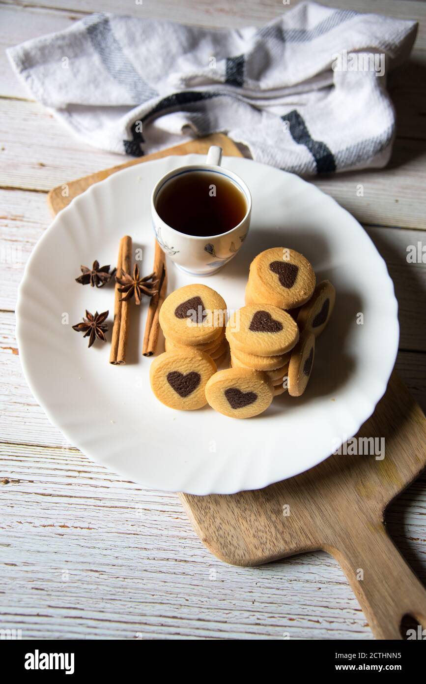 Kekse und schwarzer Kaffee auf einem weißen Teller auf einem Hintergrund Stockfoto