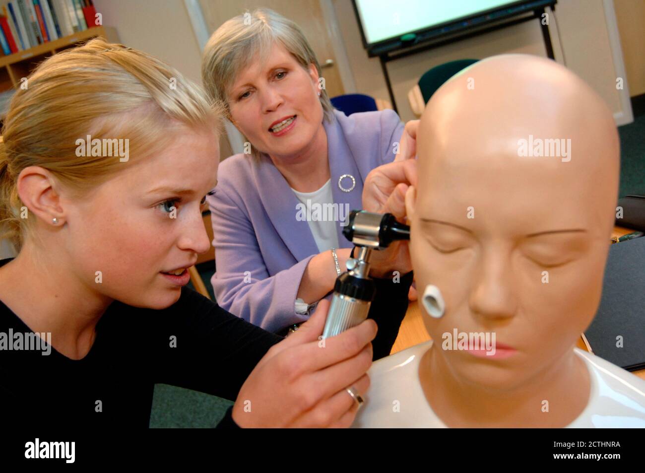 Medizinstudent lernt, wie man das Ohr mit einem Hausarzt in einer neuen Trainingsklinik untersuchen; Bradford Yorkshire UK Stockfoto