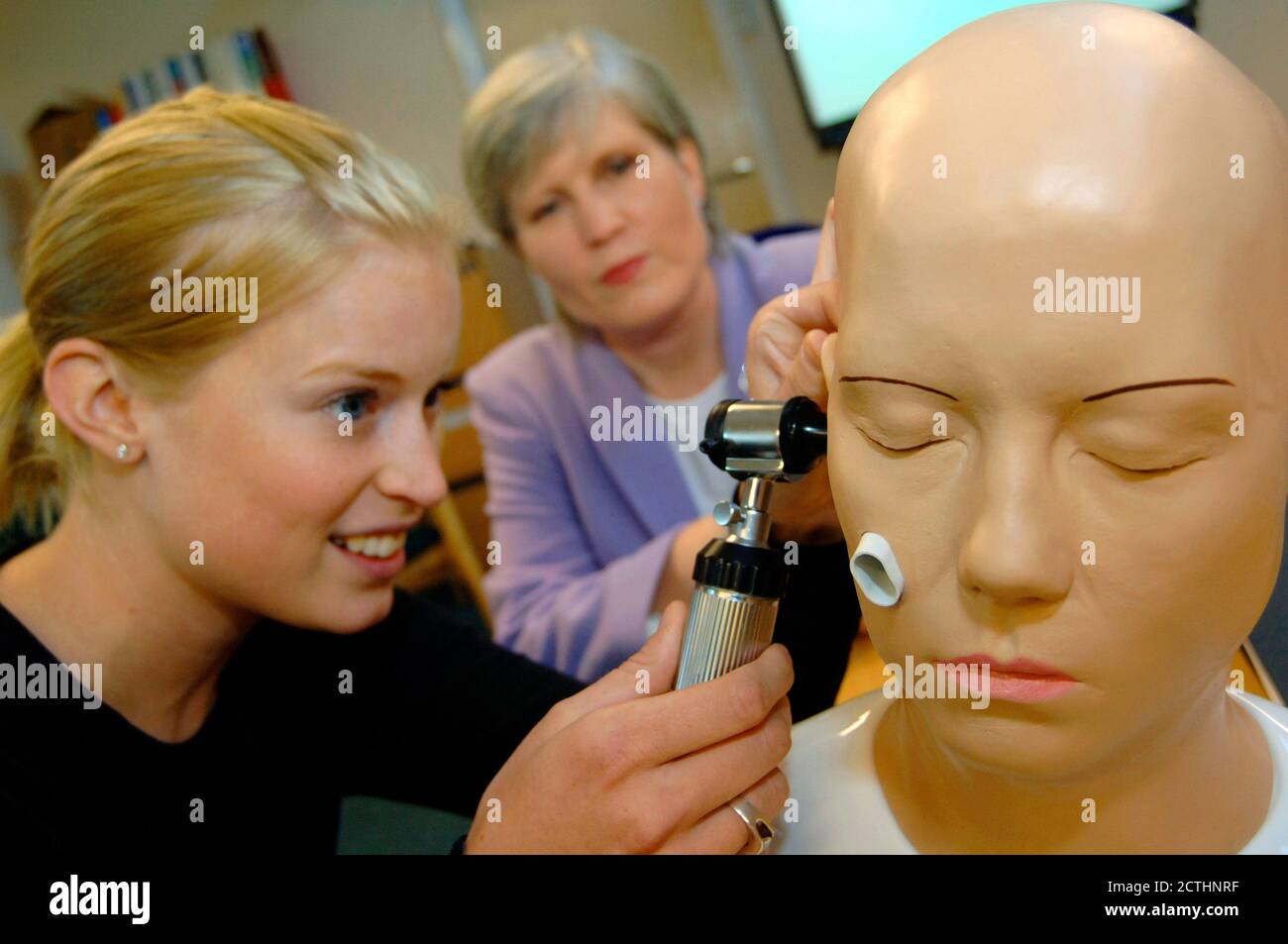 Medizinstudent lernt, wie man das Ohr mit einem Hausarzt in einer neuen Trainingsklinik untersuchen; Bradford Yorkshire UK Stockfoto