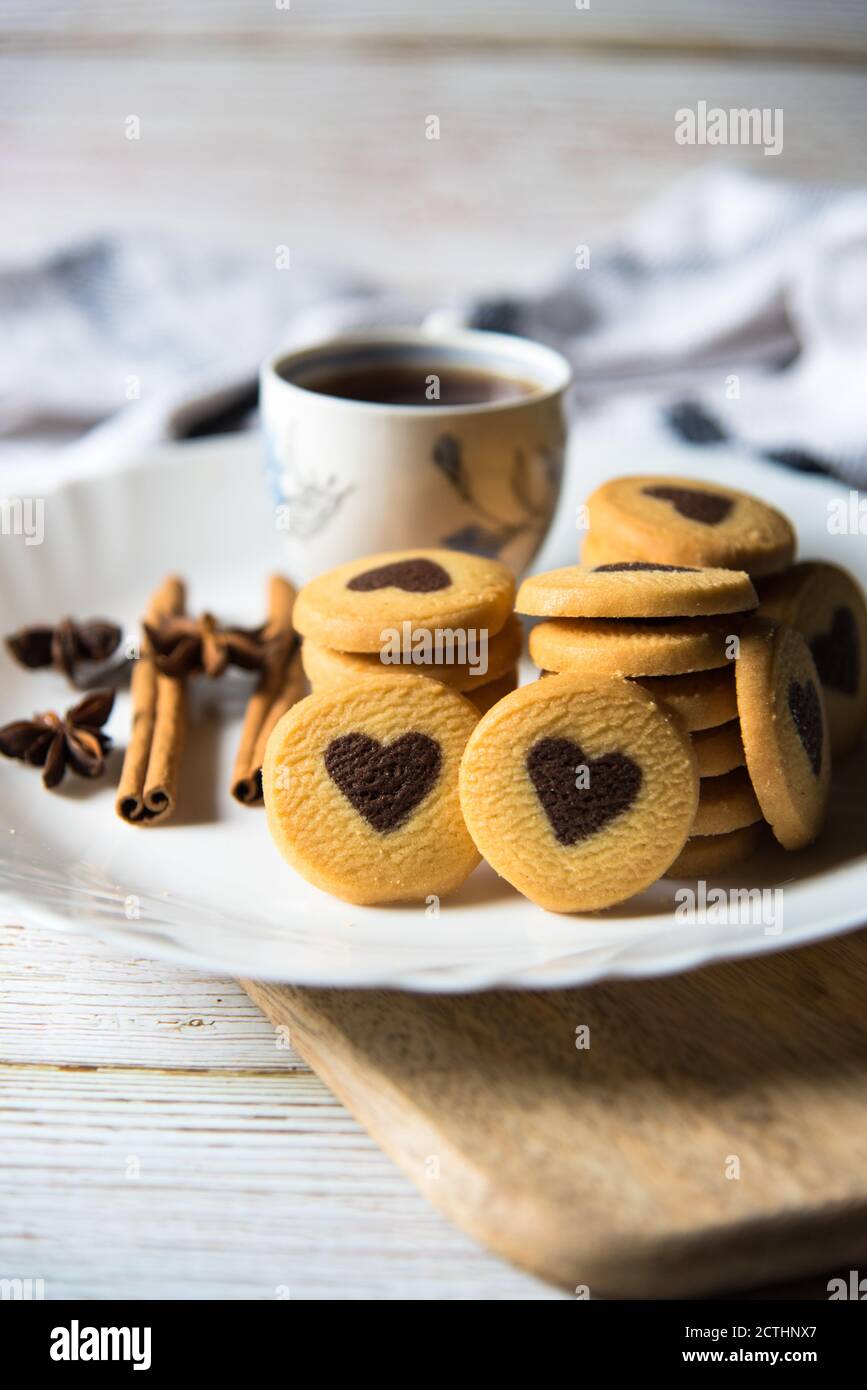 Kekse und schwarzer Kaffee auf einem weißen Teller auf einem Hintergrund Stockfoto