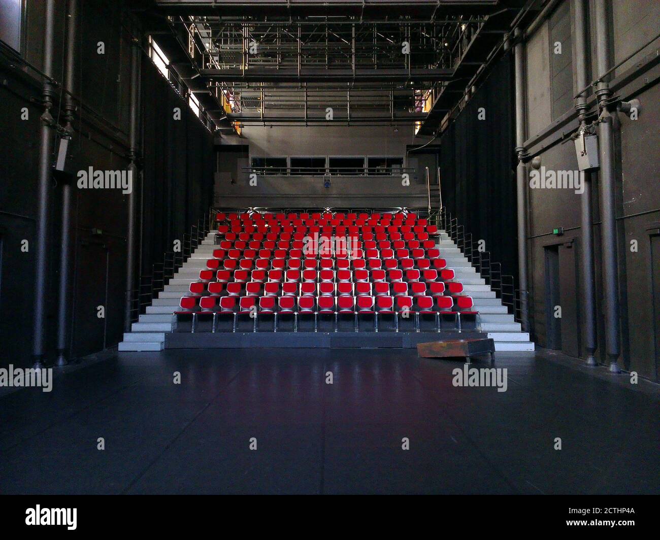 Dem Publikum gegenüber leere rote Sitze von der Bühne (POV) : abgestufte Sitzplätze im schwarzen Raum eines Theaters Stockfoto