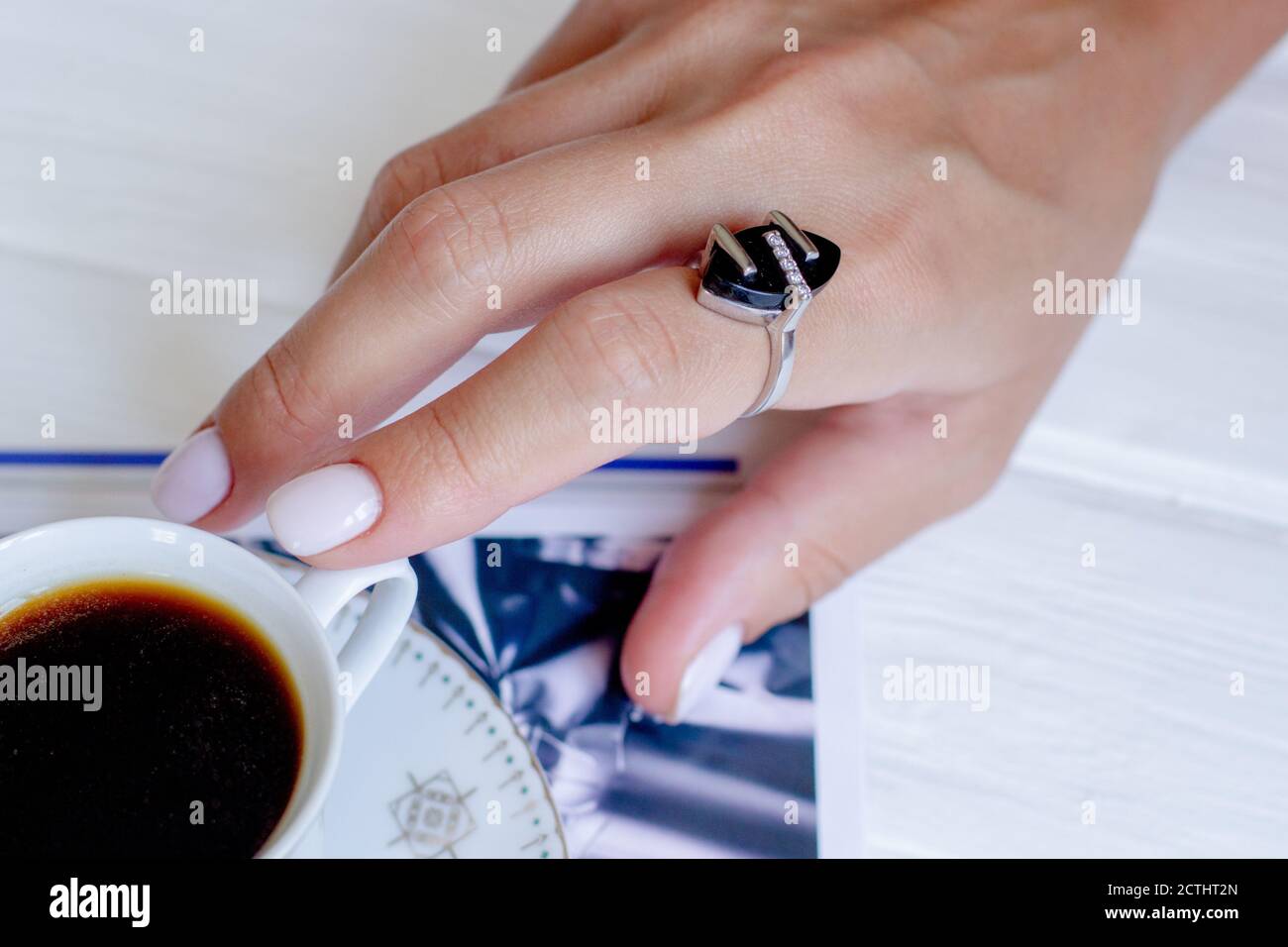 Keramik Tasse Kaffee mit Blumen in Frauen gut gepflegte Hände mit Maniküre. Stockfoto