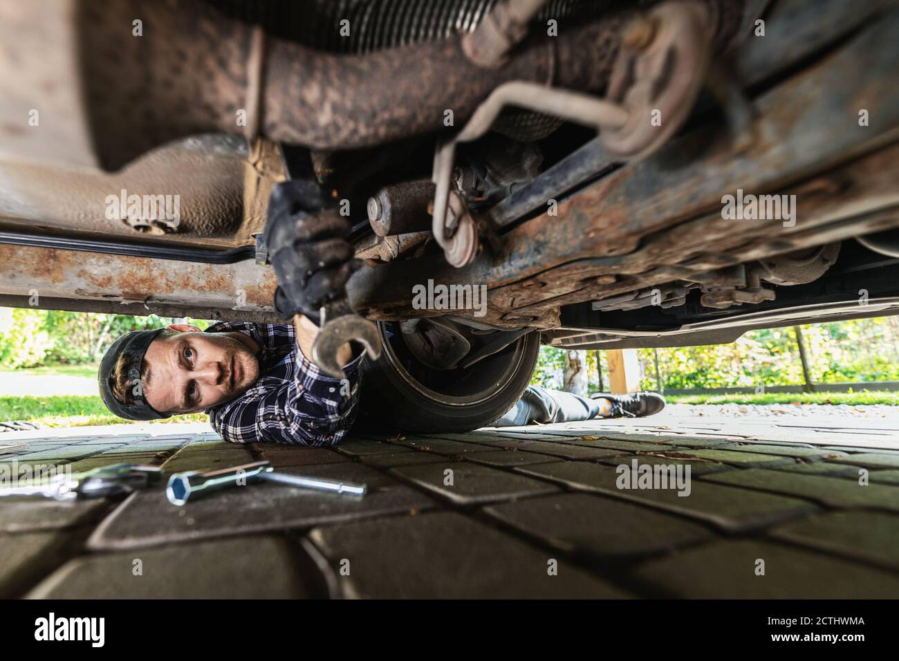 Mann repariert Boden von rostigen alten Auto. Mechaniker arbeiten Stockfoto