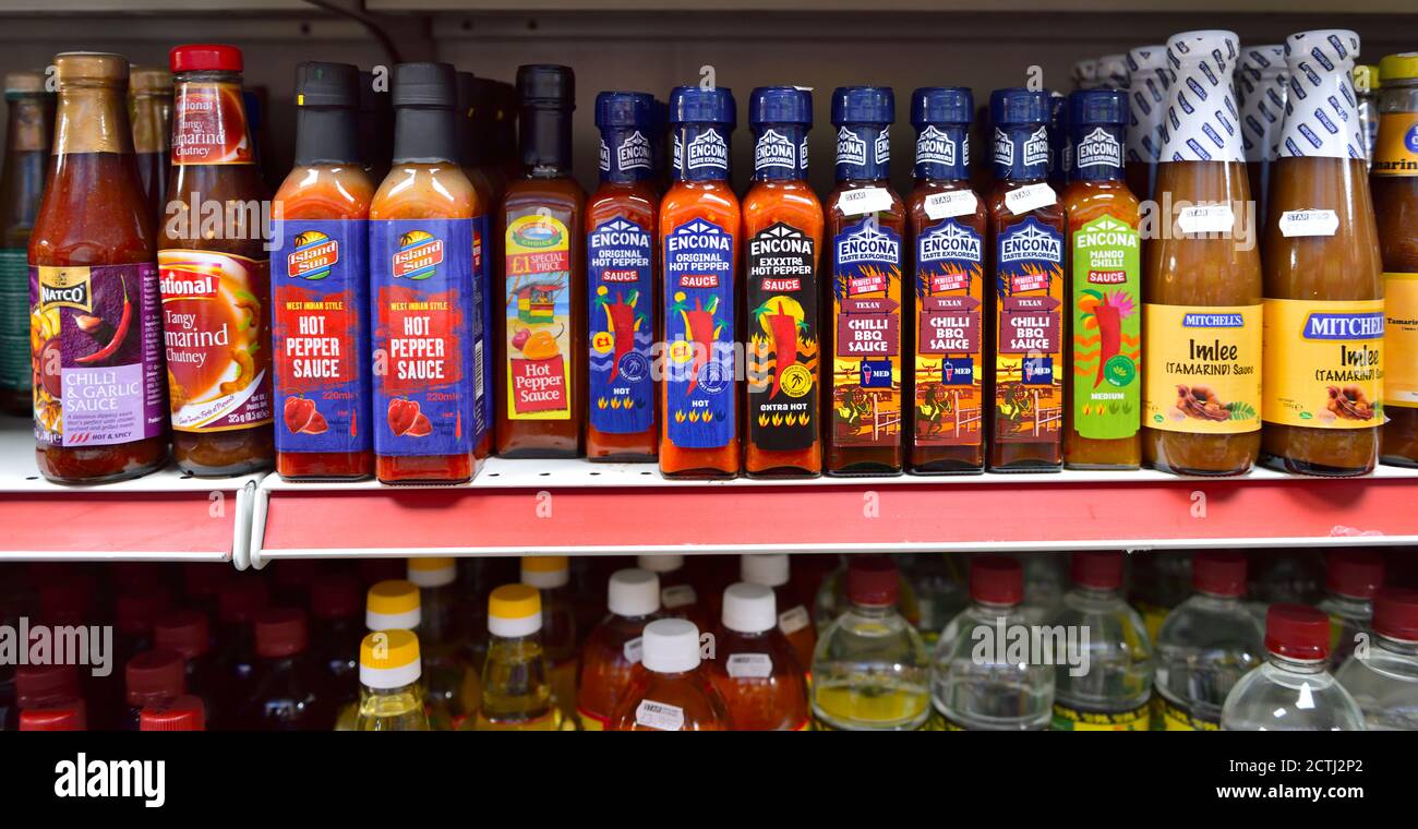 Flaschen mit verschiedenen scharfen Chilisaucen auf dem Regal Stockfoto