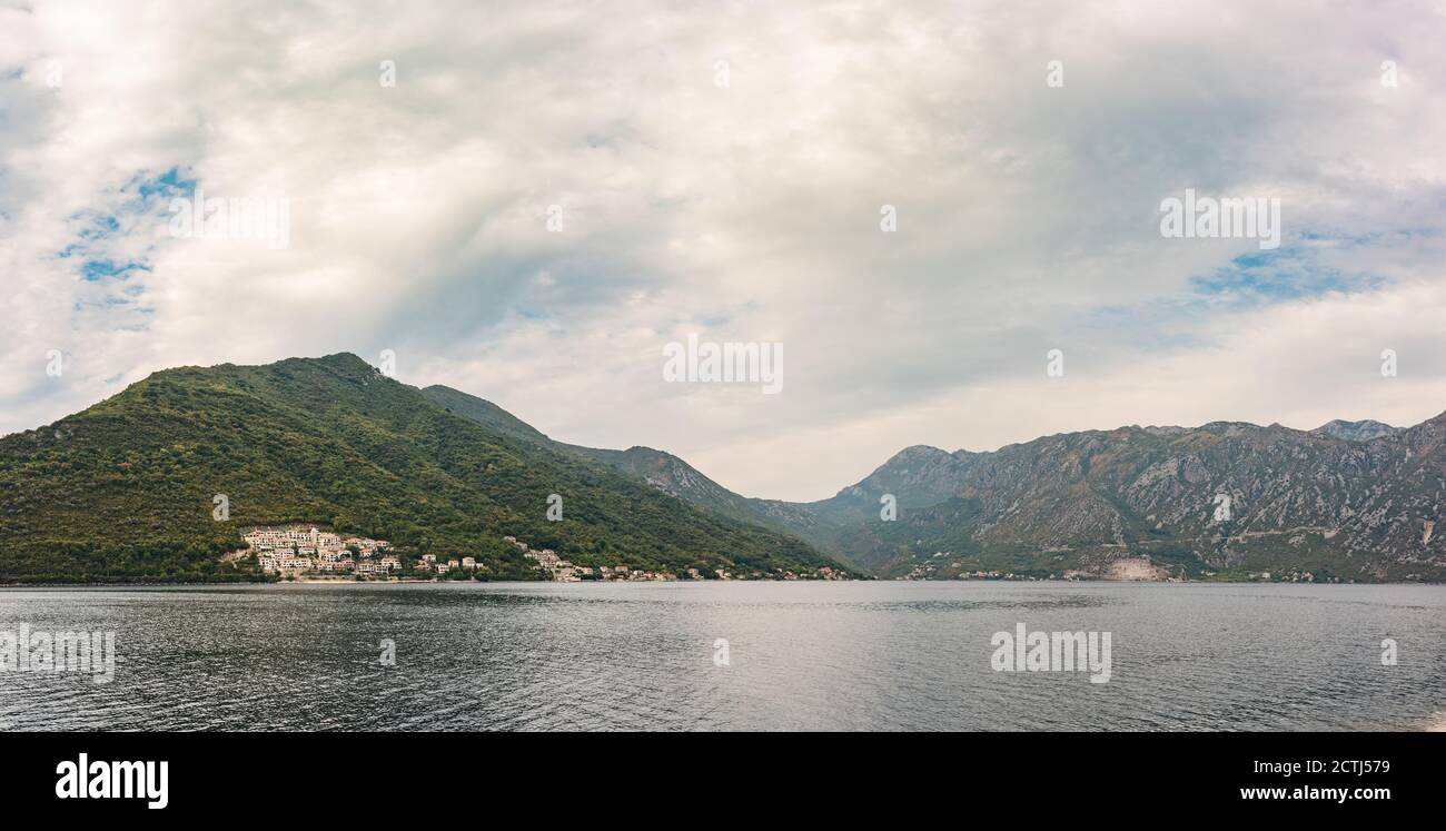 Panorama an der Bucht von Kotor, in der Nähe von Perast, Montenegro. Kleine Dörfer und massive Berge mit stürmischen Wolken Stockfoto