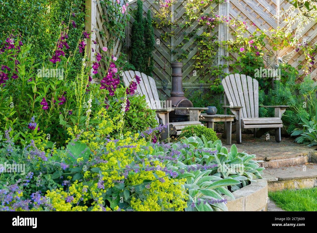 Schöner landschaftlich gestalteter privater Garten (zeitgenössisches Design, farbenfrohe Randpflanzen, Sitzecken auf der Terrasse, Zaun, dekorative Chiminea) - Yorkshire, England, Großbritannien Stockfoto