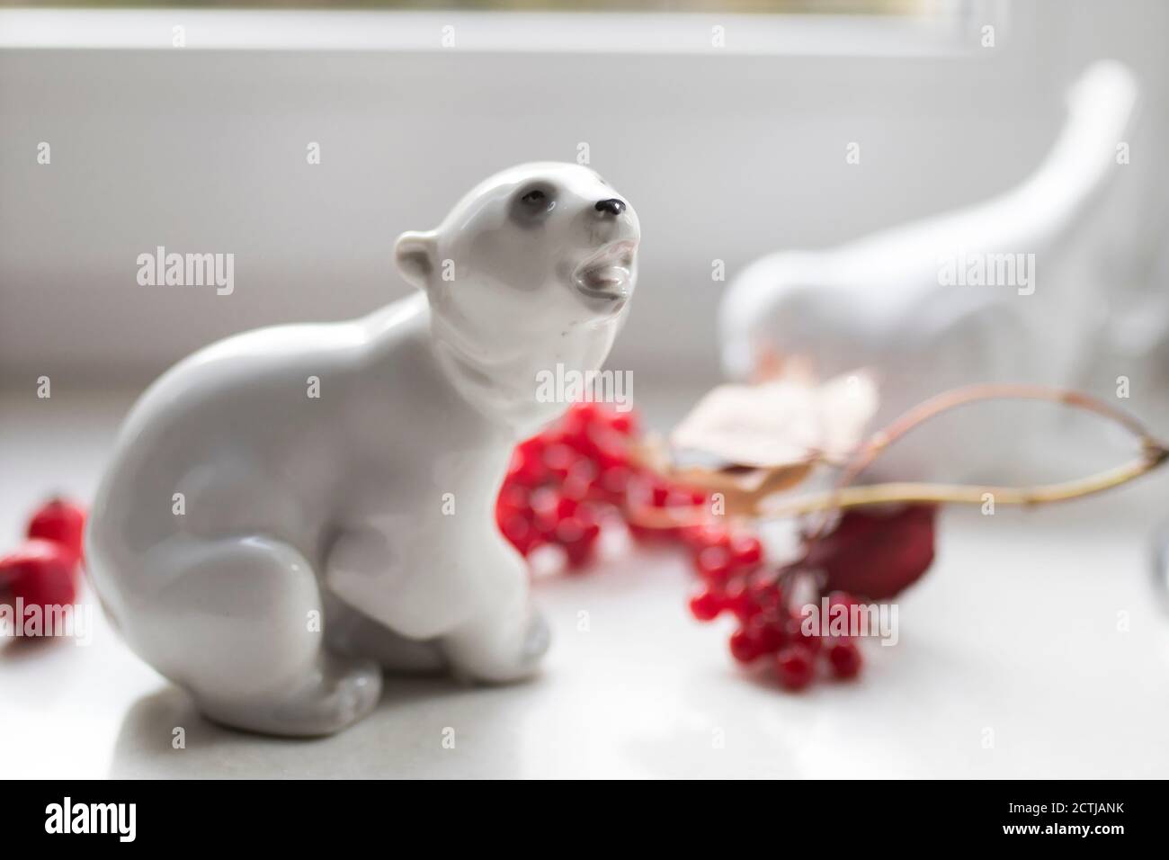 Porzellanfigur eines Eisbären mit einem Viburnum-Ast auf der Fensterbank. Foto für Instagram Stockfoto