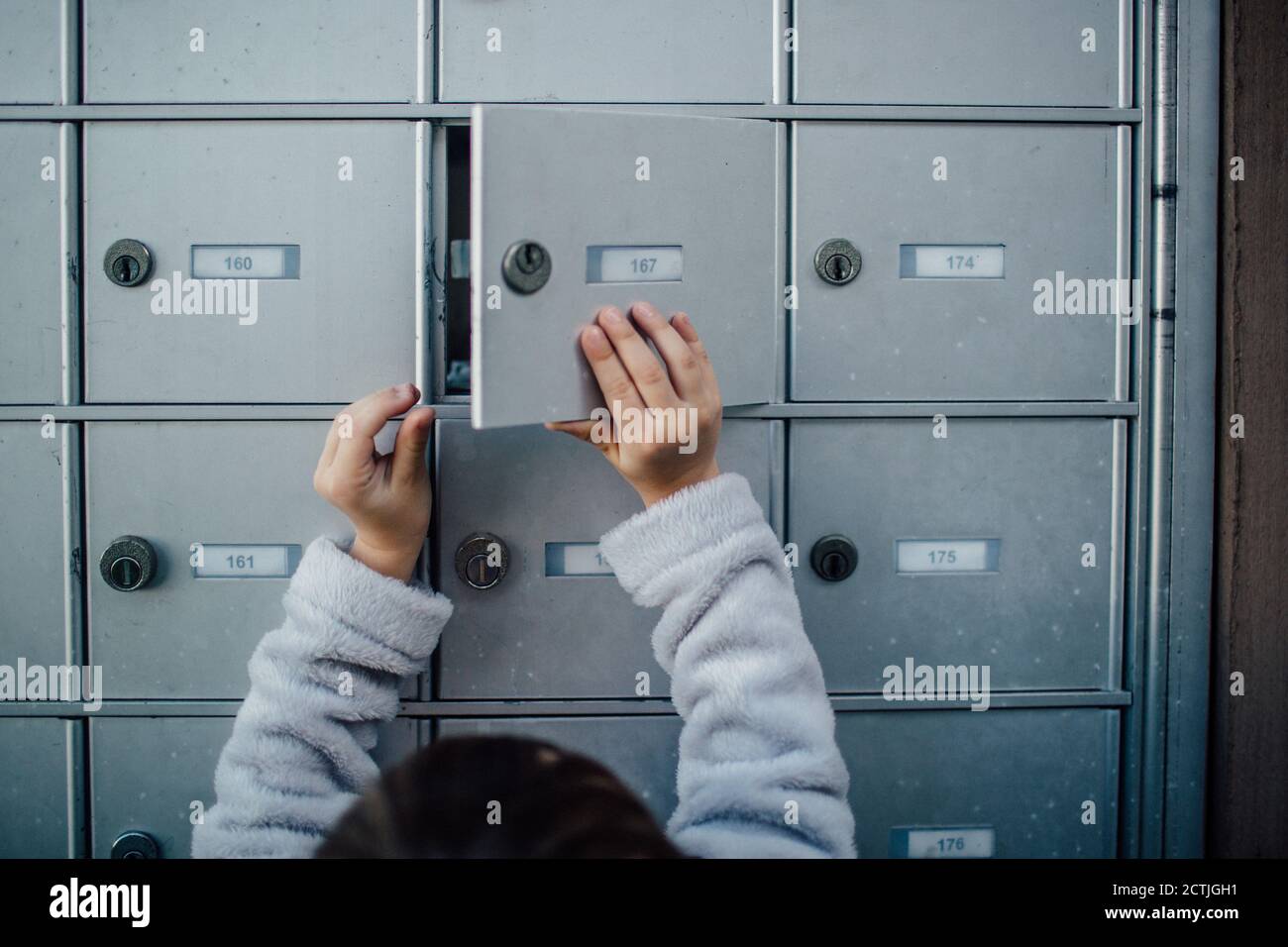 Das Kind öffnet die entriegelte Tür zur Mailbox-Einheit des Clusters Stockfoto