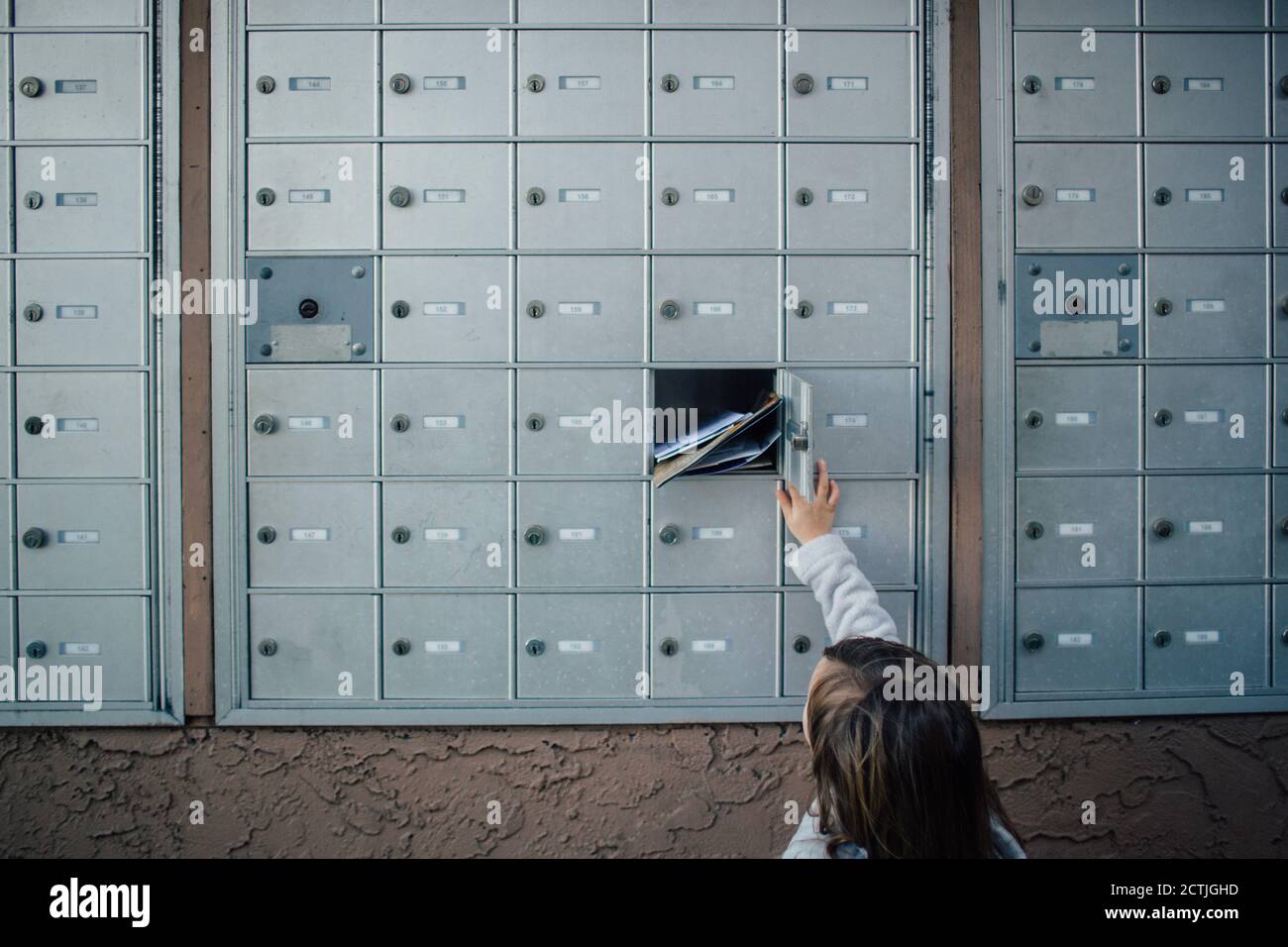 Das Kind entriegelt und öffnet die Tür zur Mailbox-Einheit des Clusters Stockfoto