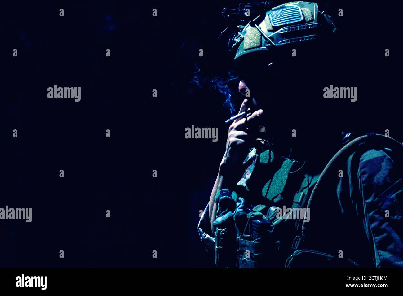 Armee Soldat in Kampfuniform und Helm, Rauchen Zigarette in der Dunkelheit. Special Operations Forces Kämpfer, ruhende Infantryman Silhouette mit Zigarette im Mund und Tabakrauch, Low-Key Stockfoto