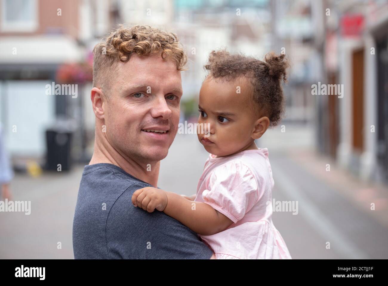 Ein Vater mit rotem Kopf hält seine Tochter Stockfoto